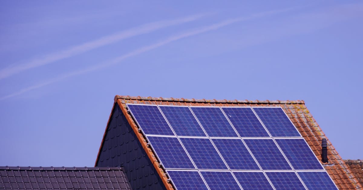 Close-up of solar panels on a tiled rooftop under a clear sky, showcasing renewable energy.